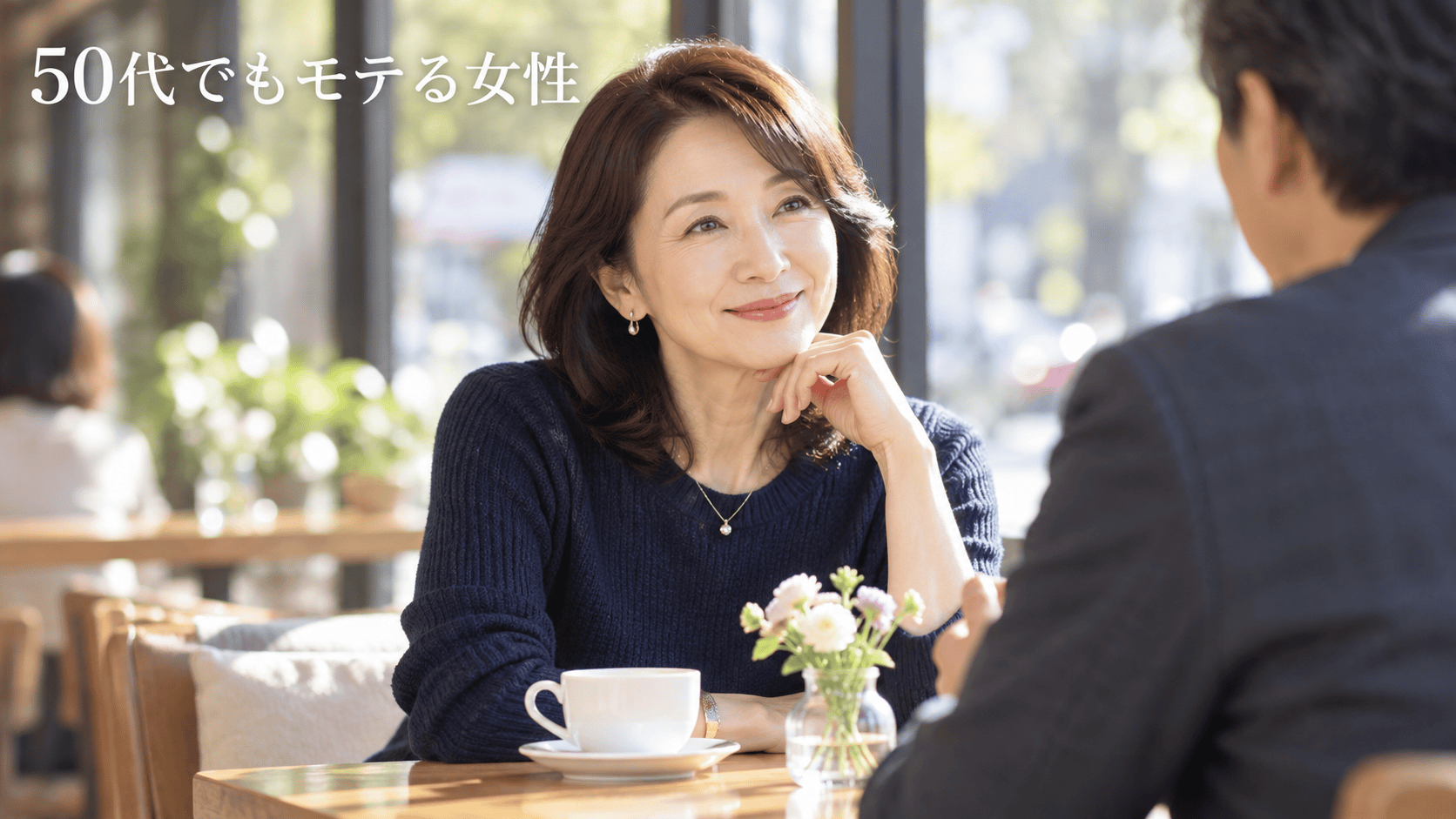 明るいカフェで男性の話を穏やかな笑顔で聞く50代女性
